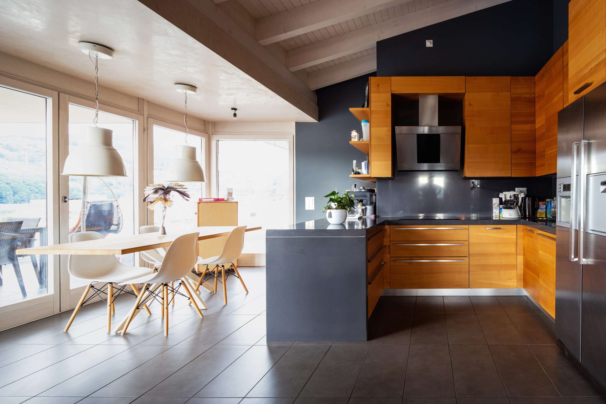 vue direct sur une cuisine en bois à droite et une table de salle à manger à gauche